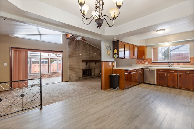 kitchen featuring sink, dishwasher, a fireplace, decorative light fixtures, and light wood-type flooring