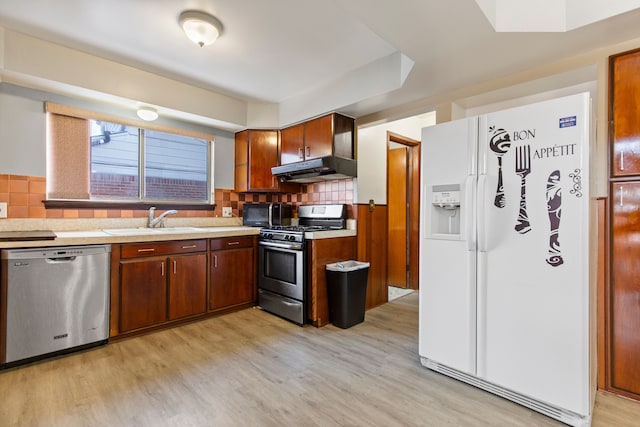 kitchen featuring tasteful backsplash, appliances with stainless steel finishes, sink, and light wood-type flooring