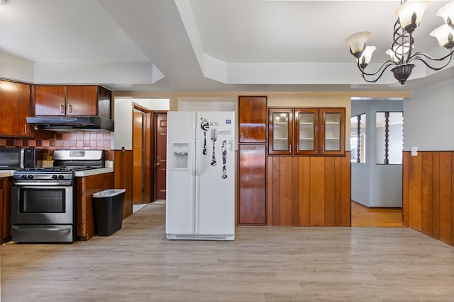 kitchen with stainless steel gas stove, hanging light fixtures, an inviting chandelier, light hardwood / wood-style floors, and white fridge with ice dispenser