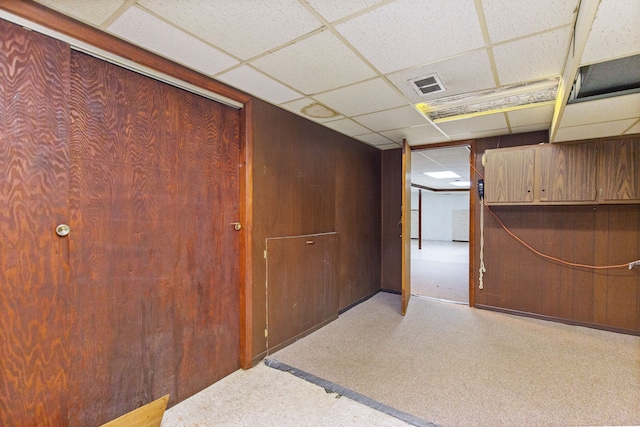 interior space featuring a drop ceiling and wooden walls