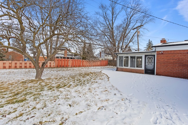 yard layered in snow featuring a sunroom