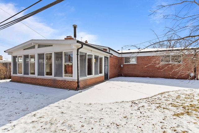 snow covered house featuring a sunroom