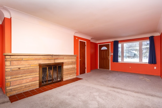 unfurnished living room with crown molding, dark colored carpet, and a stone fireplace