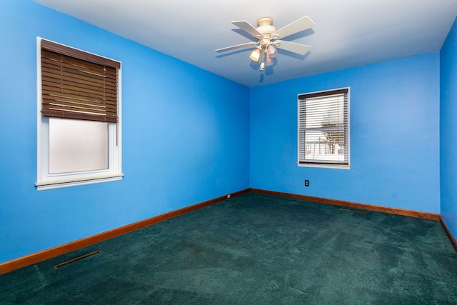 empty room with ceiling fan, visible vents, dark carpet, and baseboards