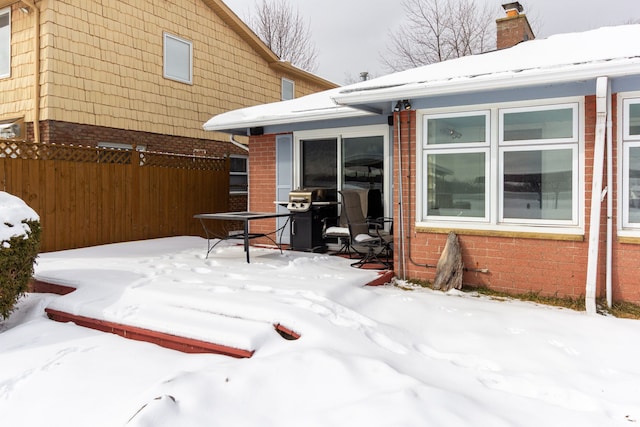 snow covered patio with fence and area for grilling