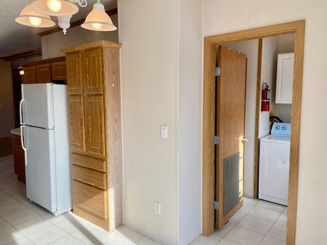 kitchen with light tile patterned floors, washer / dryer, decorative light fixtures, and white refrigerator