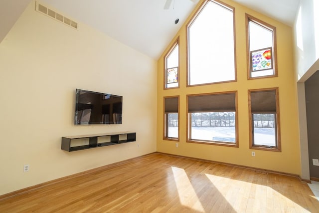 unfurnished living room with high vaulted ceiling and light wood-type flooring