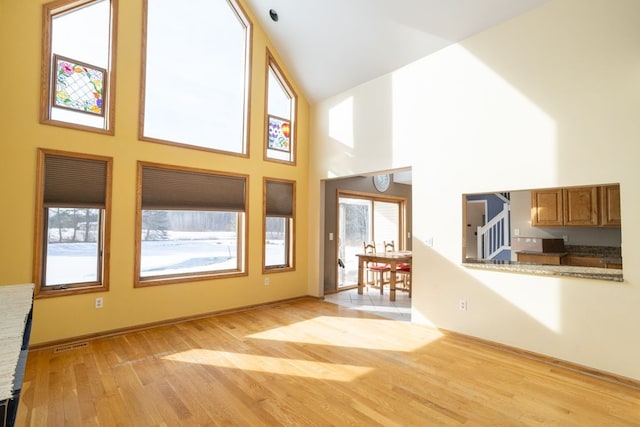 unfurnished living room featuring light hardwood / wood-style flooring and a high ceiling