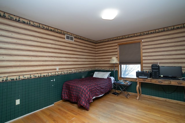 bedroom featuring hardwood / wood-style floors and log walls