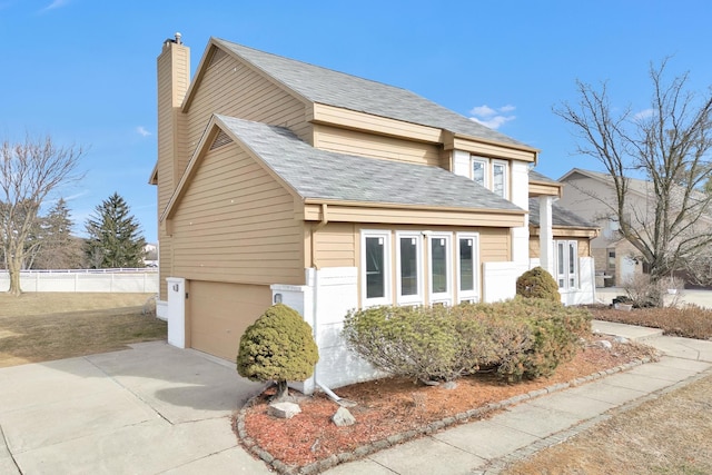 view of front facade with driveway, fence, roof with shingles, an attached garage, and a chimney