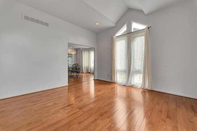 unfurnished room with light wood-type flooring, visible vents, baseboards, and vaulted ceiling