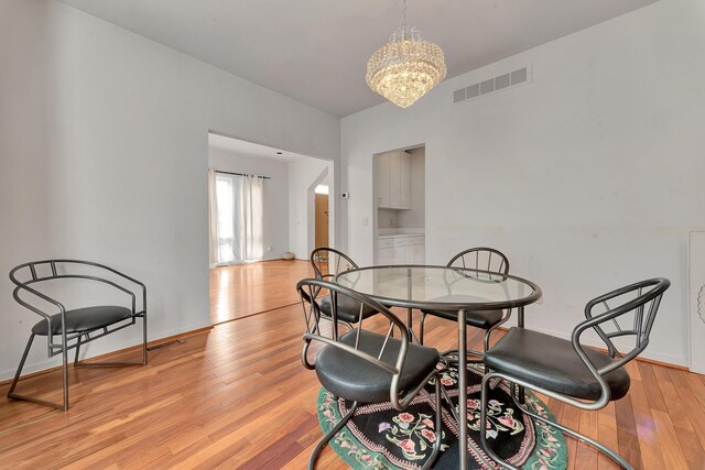 dining space with visible vents, baseboards, light wood-style floors, and a chandelier