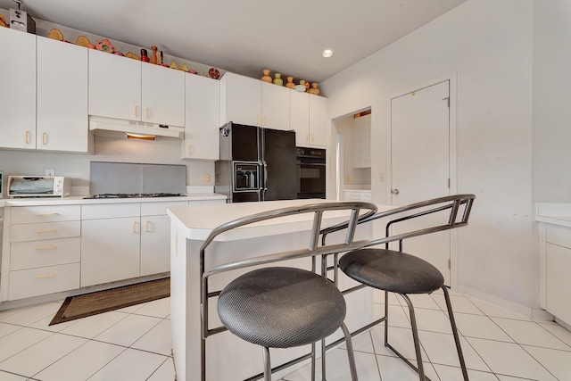 kitchen featuring black appliances, under cabinet range hood, light tile patterned flooring, white cabinets, and light countertops