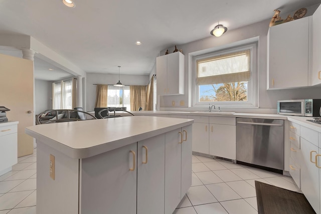 kitchen featuring light tile patterned floors, a sink, light countertops, appliances with stainless steel finishes, and a wealth of natural light