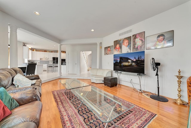 living room featuring decorative columns, recessed lighting, visible vents, and light wood finished floors