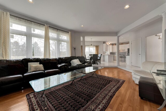 living area with decorative columns, recessed lighting, and light wood finished floors