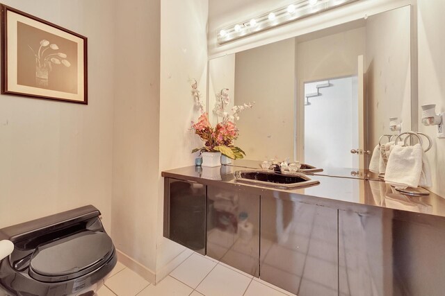 bathroom with tile patterned floors, baseboards, toilet, and a sink