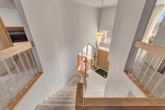 stairway featuring a high ceiling, a notable chandelier, and a wealth of natural light