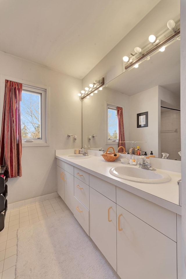 bathroom featuring double vanity, a healthy amount of sunlight, tile patterned floors, and a sink