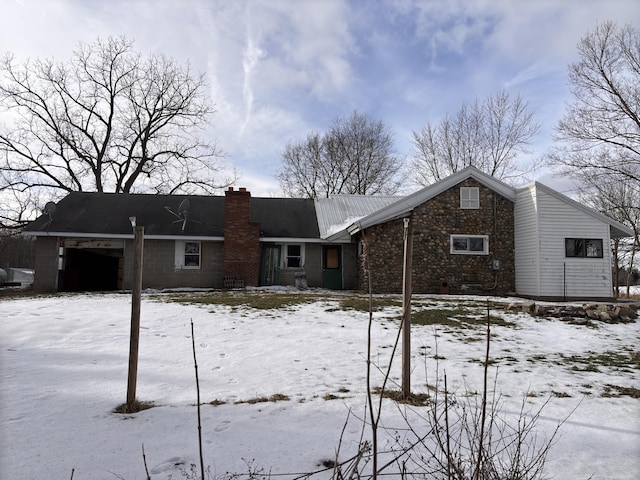 snow covered rear of property with a garage