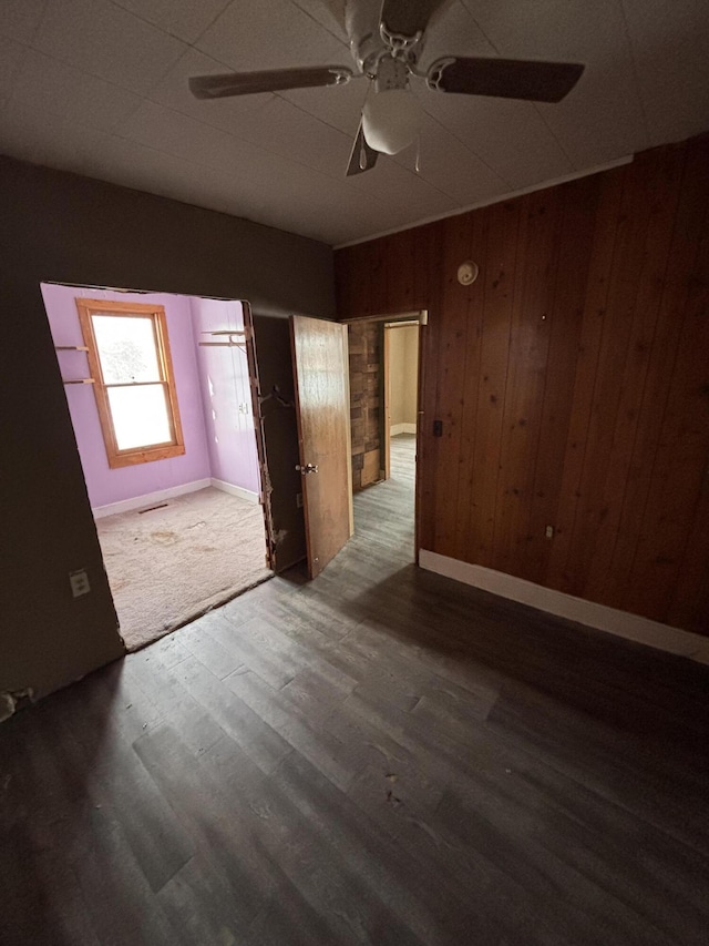 unfurnished bedroom featuring ceiling fan, hardwood / wood-style floors, and wooden walls