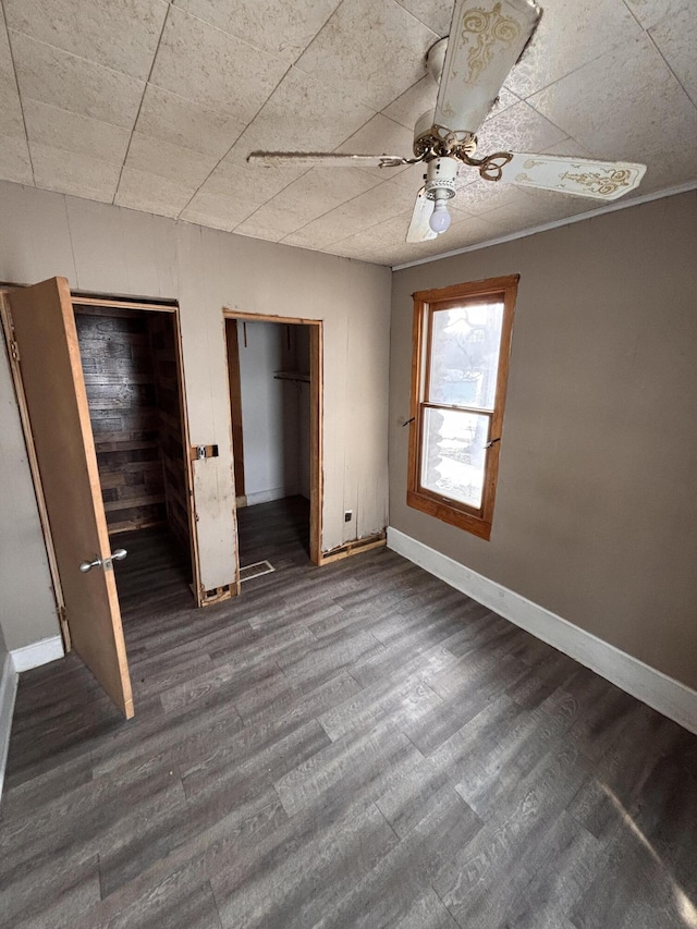 unfurnished bedroom with multiple closets, dark wood-type flooring, and ceiling fan