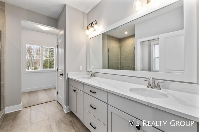 full bathroom featuring double vanity, a shower stall, baseboards, and a sink