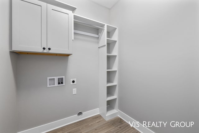 clothes washing area featuring washer hookup, cabinet space, electric dryer hookup, wood finished floors, and baseboards