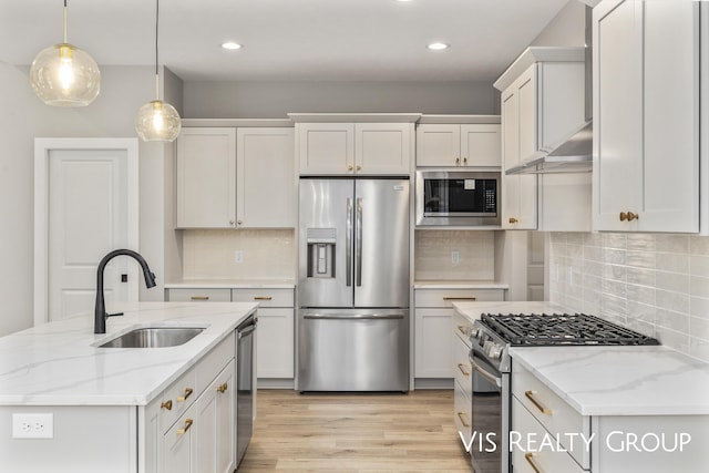 kitchen featuring light stone counters, pendant lighting, stainless steel appliances, white cabinets, and a sink