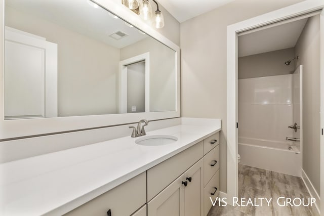 bathroom featuring visible vents, toilet, wood finished floors, bathtub / shower combination, and vanity