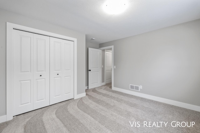 bedroom with light carpet, baseboards, visible vents, and a closet