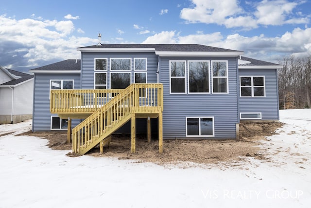 snow covered house with stairs and a wooden deck
