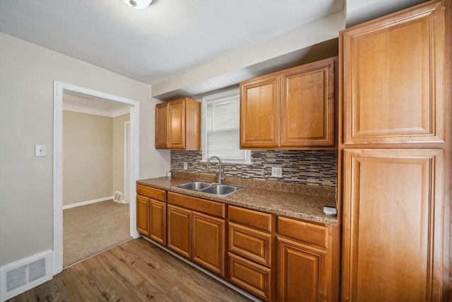 kitchen with tasteful backsplash, sink, and light hardwood / wood-style flooring