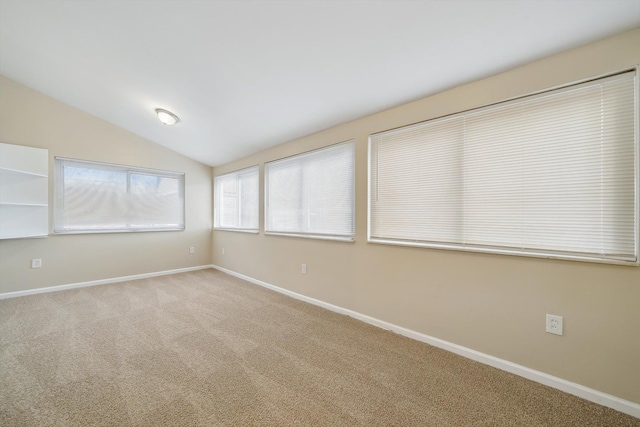 carpeted spare room featuring vaulted ceiling