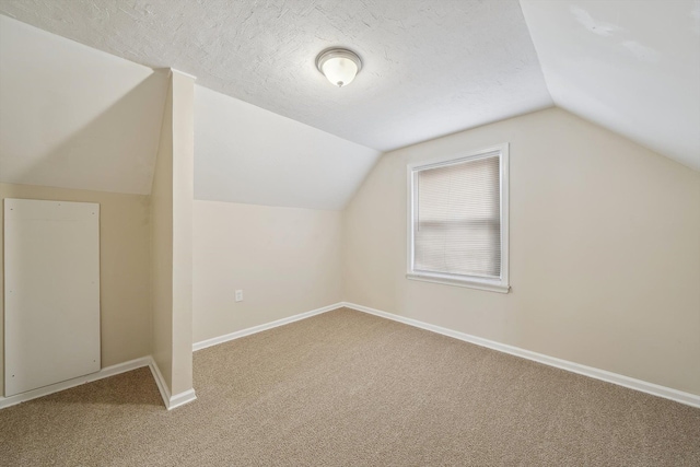 bonus room featuring lofted ceiling, carpet flooring, and a textured ceiling