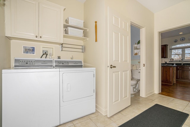 laundry area featuring light tile patterned flooring, cabinets, sink, and washing machine and dryer