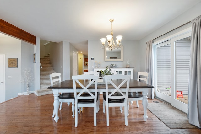 dining area with hardwood / wood-style flooring and an inviting chandelier