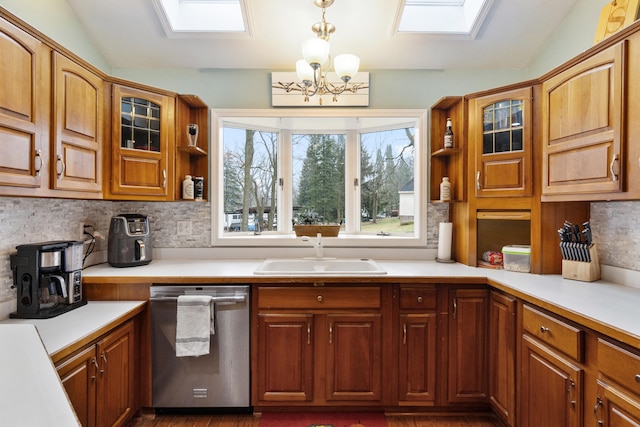 kitchen with stainless steel dishwasher, vaulted ceiling with skylight, sink, and backsplash