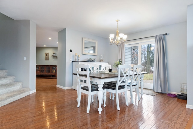 dining area with hardwood / wood-style floors and a notable chandelier