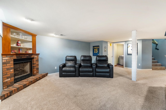 home theater featuring washer / clothes dryer, a brick fireplace, and light carpet