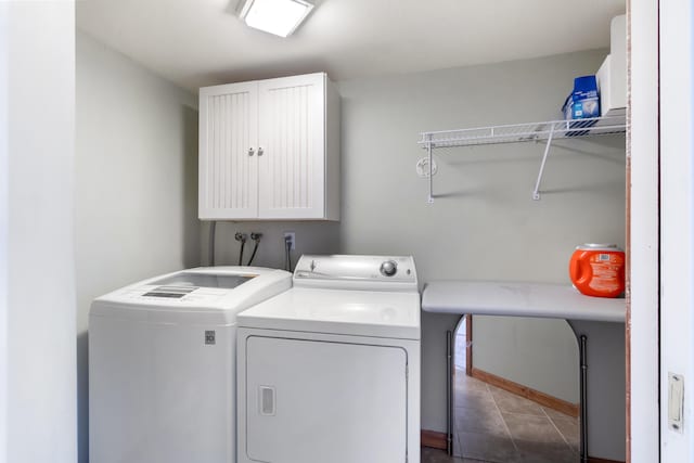 clothes washing area featuring cabinets, dark tile patterned floors, and independent washer and dryer