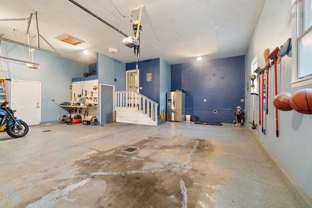 garage featuring a garage door opener, a workshop area, and stainless steel refrigerator with ice dispenser