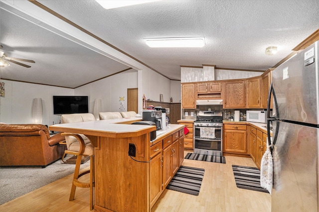 4348 S Grandview Hwy, Harrietta, MI 49638 - kitchen featuring vaulted ceiling, appliances with stainless steel finishes, a breakfast bar, a center island, and crown molding