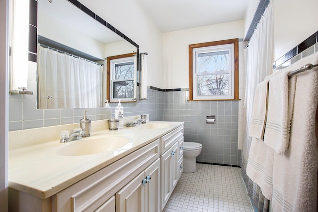 bathroom with tile walls, vanity, tile patterned floors, and a healthy amount of sunlight