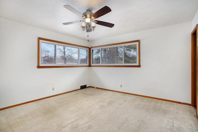 carpeted spare room featuring ceiling fan and a wealth of natural light