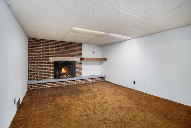 basement with a brick fireplace, carpet floors, and a paneled ceiling