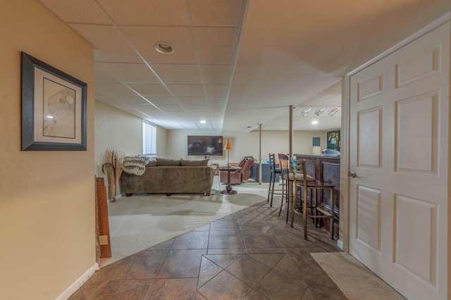 living room with dark tile patterned floors, indoor bar, and a paneled ceiling