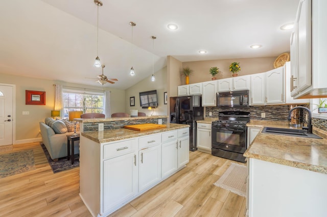 kitchen with sink, white cabinetry, hanging light fixtures, black appliances, and a kitchen island