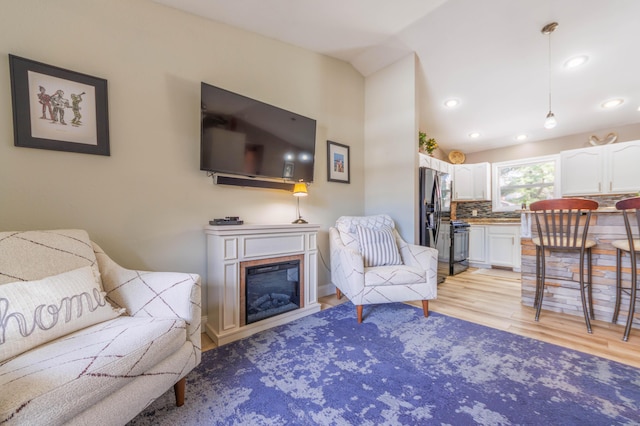 living room with vaulted ceiling and light wood-type flooring