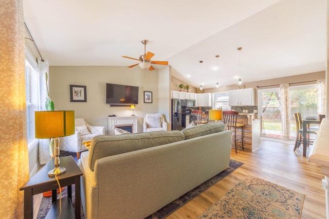 living room featuring vaulted ceiling, ceiling fan, and light wood-type flooring